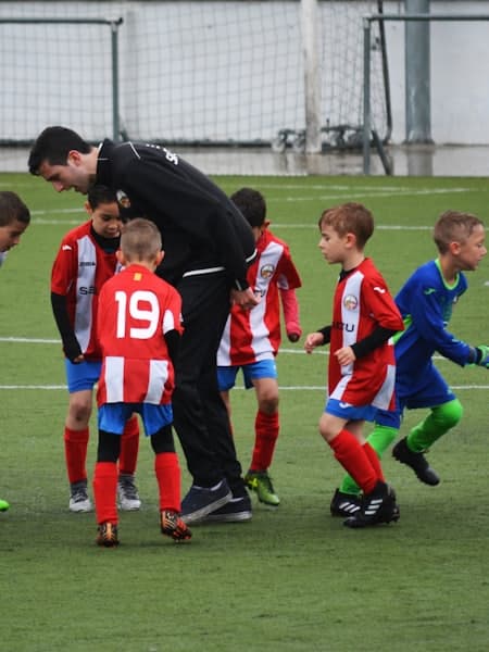 Coach talking to a youth team on the pitch