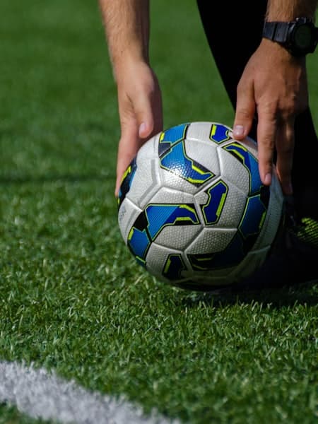 Hands placing the match ball on the pitch