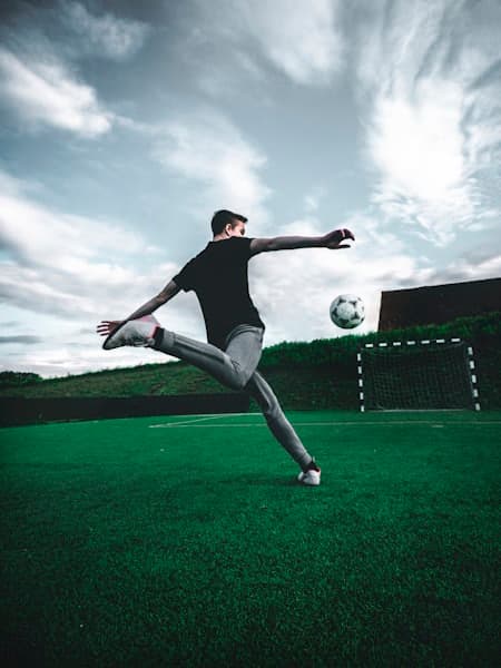 Player volleying in front of a goal under a grey sky