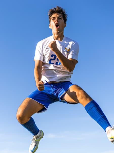 Player celebrating a goal against a clear sky